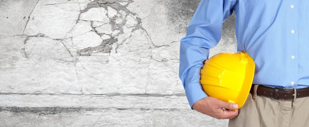 Construction worker with helmet over gray wall background.
